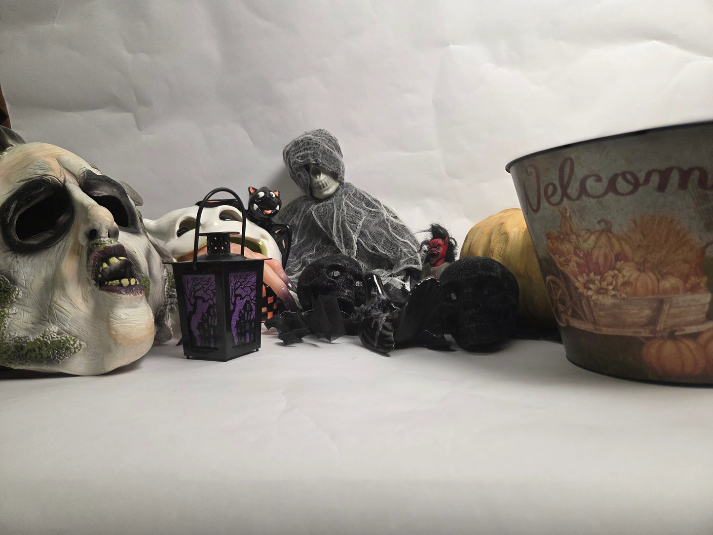 Halloween-themed decorations including a skull mask, black cat, and ghost figure on a white background.