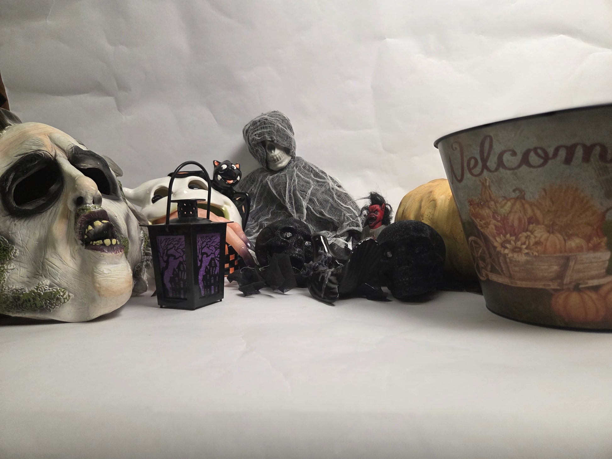 Halloween-themed decorations including a skull mask, black cat, and ghost figure on a white background.