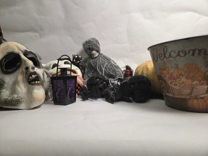 Halloween-themed decorations including a skull mask, black cat, and ghost figure on a white background.